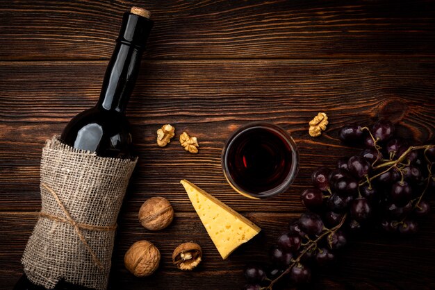 Red wine, grape, cheese and walnut on dark wooden background.