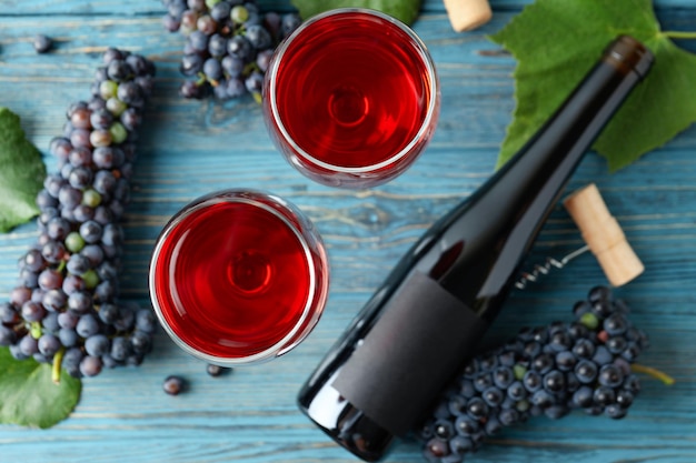 Red wine, grape, cork and corkscrew on wooden table