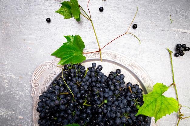 Red wine grapes in silver tray on grey background.