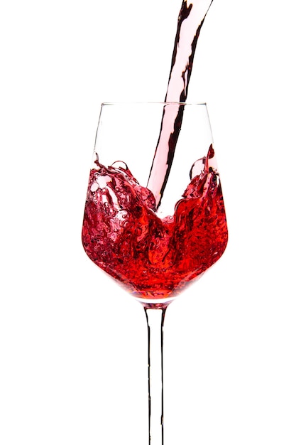 Red wine is pouring into a glass goblet on a white background. Alcoholic drinks. High quality photo