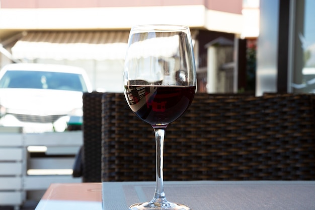 Red wine in a large glass on the table in a summer cafe on the veranda