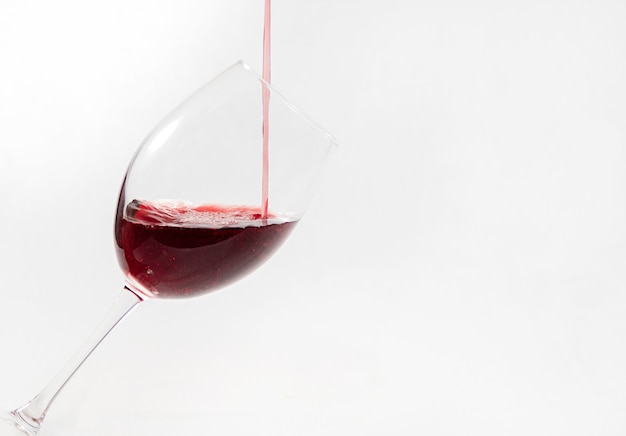 Red wine poured in a glass isolated on white