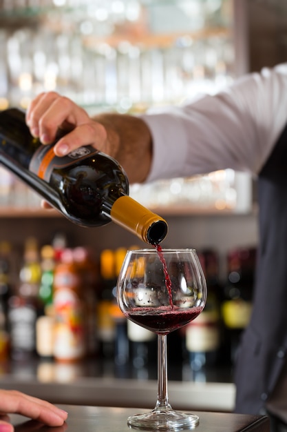 Red wine pouring in glass at bar