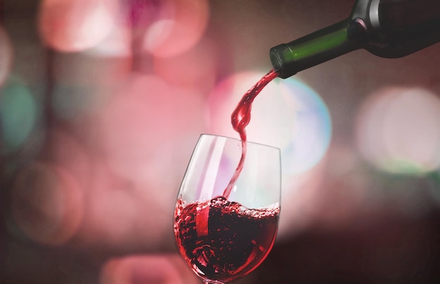 Red wine pouring into glass on dark background