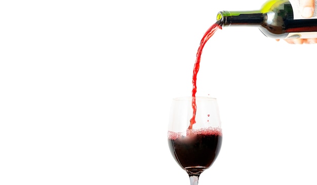 Vino rosso che versa nel bicchiere isolato