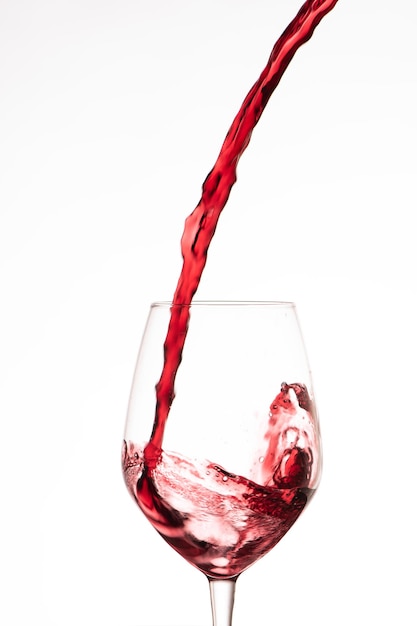 Red wine pouring in a wine glass, on a white background