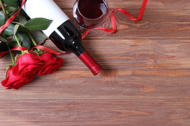 Red wine and roses on the table valentines day background