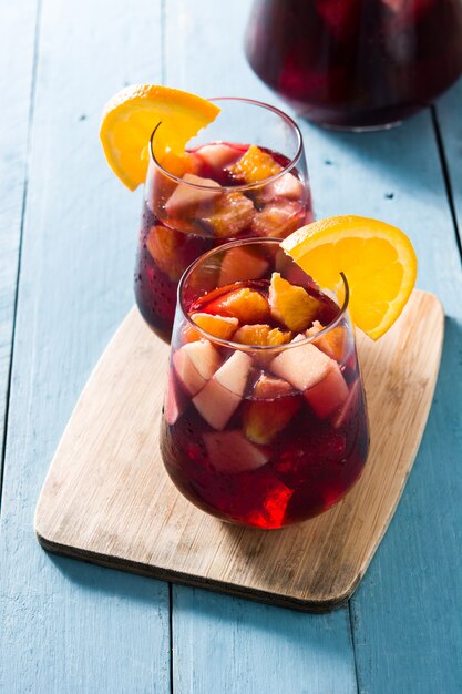 Foto sangria del vino rosso in vetro sulla tavola di legno blu