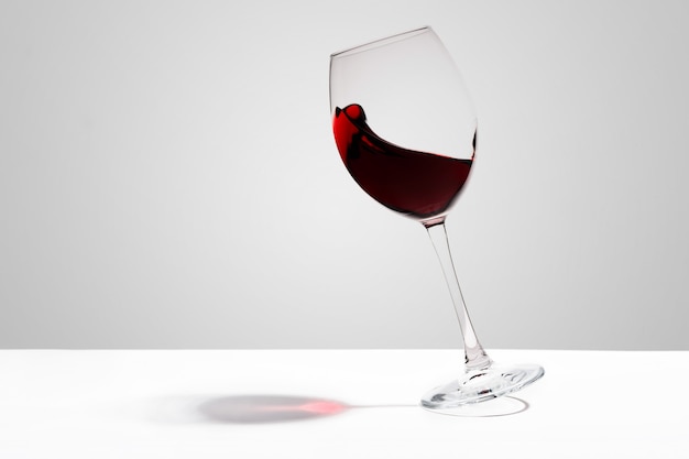 Red wine splashes in a glass on white