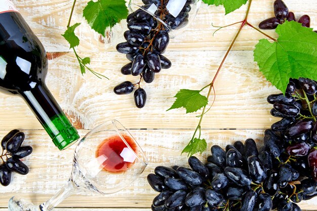 Foto vino rosso con bottiglia, bicchiere e uva.