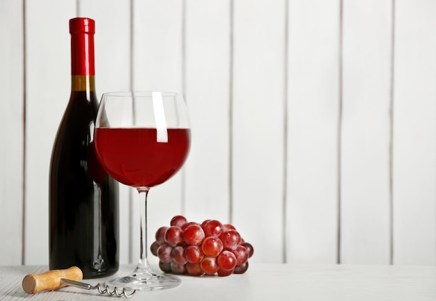 Red wine with grape on wooden wall background