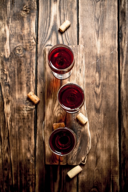 Red wine on wooden Board with stoppers and a corkscrew on wooden table.