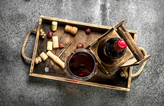 Red wine on wooden tray on rustic table.