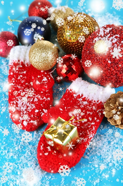 Red winter mittens with Christmas toys on blue wooden table