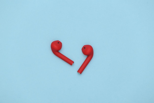 Red wireless headphones on blue background. Top view