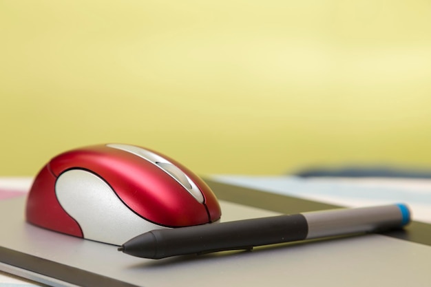 Red wireless mouse and pencil on a graphic tablet computer peripherals