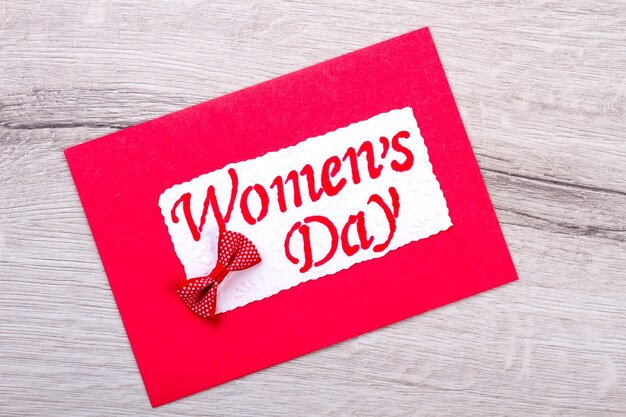 Red Women's Day greeting card. Combination of card and bow. Congratulate women with present. Creativity in action.