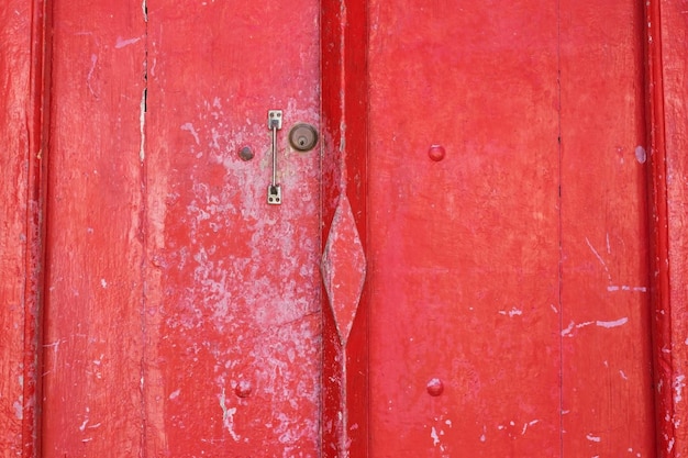 Foto porta antica in legno rosso con piccola maniglia