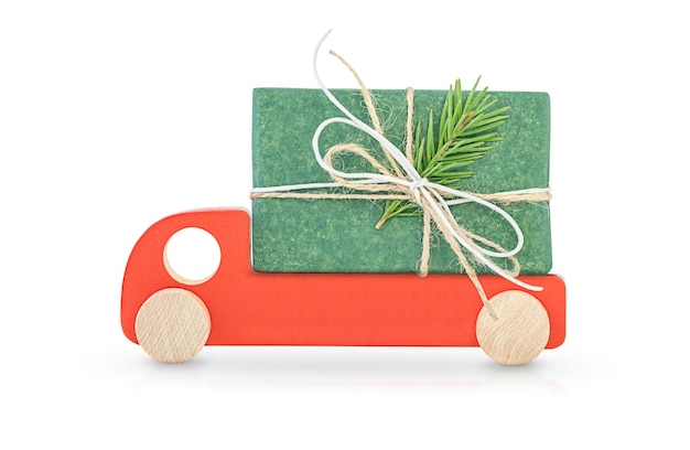 Automobile di legno rossa che porta un regalo di natale isolato su fondo bianco