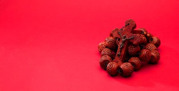 red wooden catholic rosary on a red background, space for text