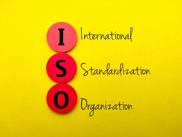 Foto cubo di legno rosso con la parola organizzazione internazionale di standardizzazione iso su sfondo giallo