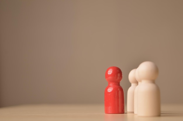 Red wooden doll figure standing out from the crowd