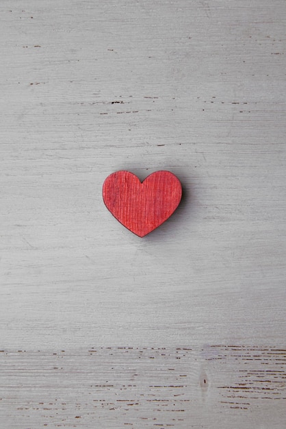 Red wooden heart on a light wooden background. Element for design. Top view with copy space. Flat lay