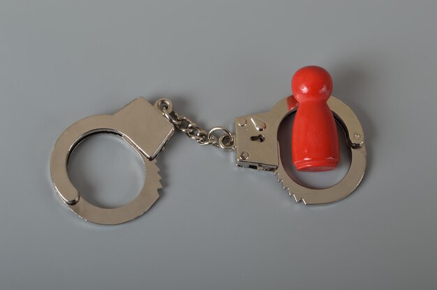 Red wooden people of figure with handcuff locked Handcuffed convict law offender and justice concept