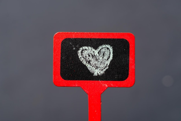 Red wooden plaque surface painted with a heart Black background