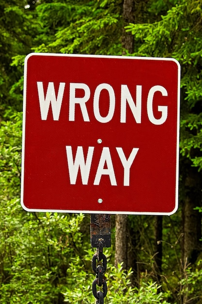 Photo a red wrong way sign against trees