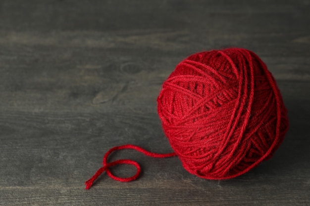 Red yarn ball on gray wooden table