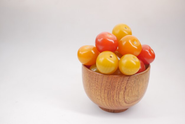 Red and yellow color cherry tomato in a bowl on white background