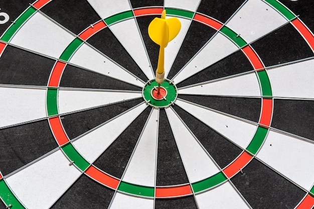 Red and yellow dart arrows hitting in the target center of\
dartboard success hitting target aim goal achievement concept