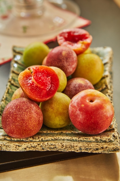 Red and yellow fresh plums on plate ready to eat.