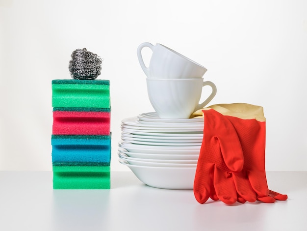 Red and yellow gloves a set of dishes and cleaning products on a light background