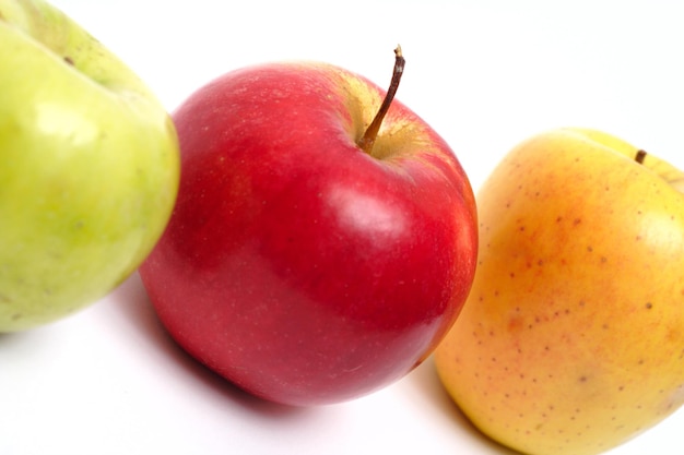 Red, yellow and green apples in a row on a white background