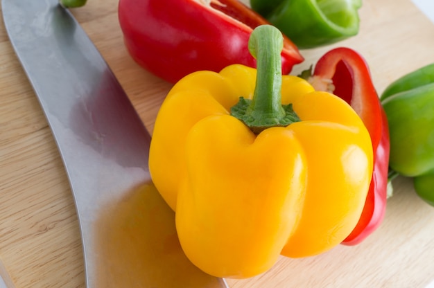 Red yellow green bell pepper with knife on cutting board