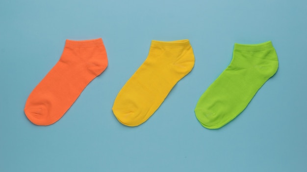 Red, yellow and green short socks on a blue background. A stylish sports accessory.