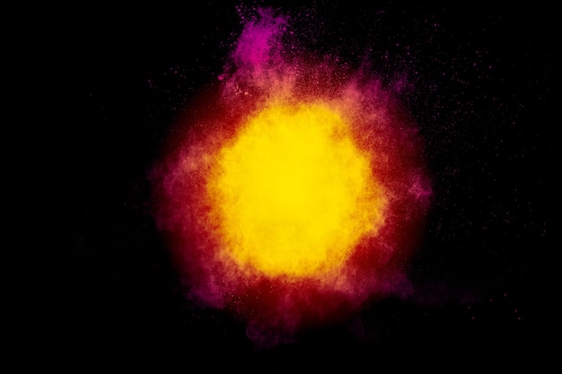 Red yellow powder explosion cloud on black background. Freeze motion of red yellow color dust particles splashing.