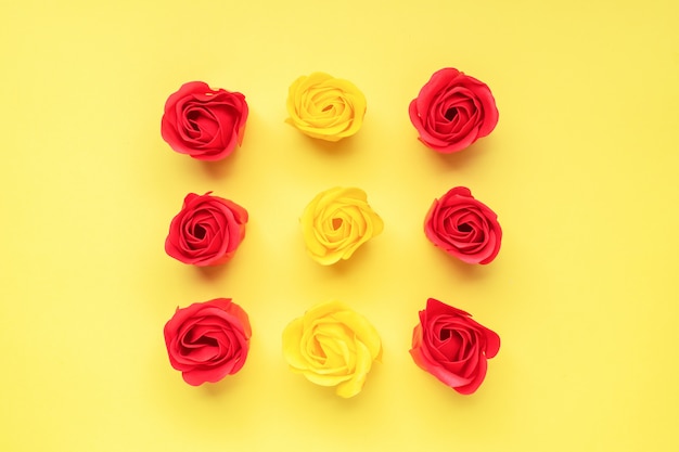 Germogli rosa rossi e gialli su sfondo giallo. il concetto di san valentino, romanticismo di nozze. flat lay copia spazio.