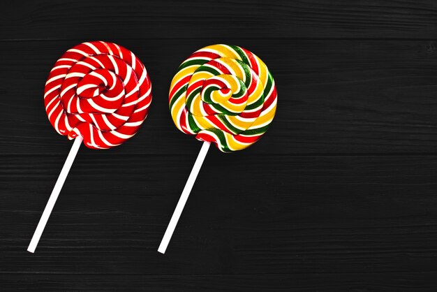 red and yellow round lollipops on black background with texture sweet