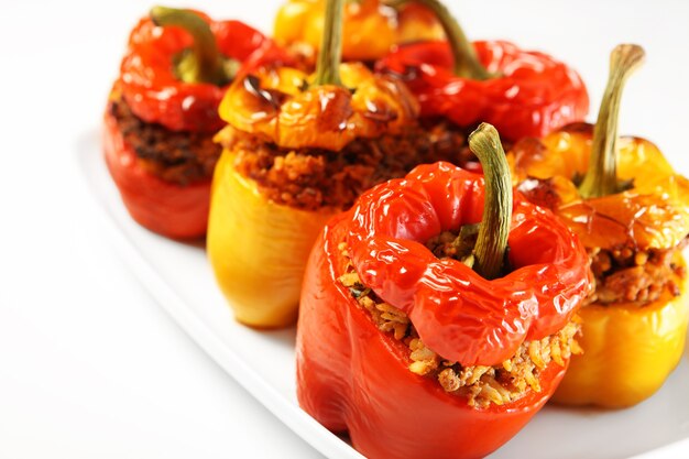 red and yellow stuffed peppers baked and served on a white plate