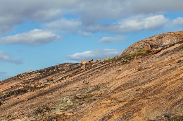 Redbrown mountainside against a blue sky with clouds bright landscape on a sunny day Stones and sand climbing to the top