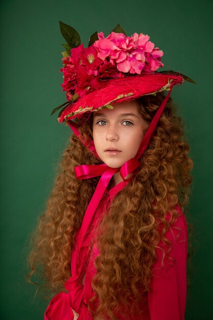 Redhair beautiful girl with curly afro curls in bright pink dress on green background.