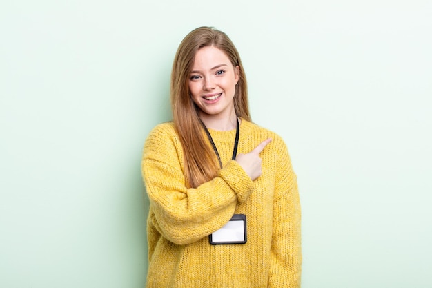 Redhair smiling cheerfully, feeling happy and pointing to the side. accreditation card concept