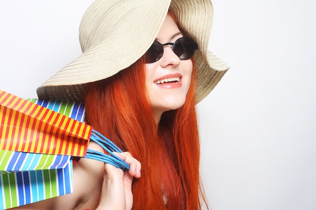Redhair winkelende vrouw die zonnebril en hoed draagt