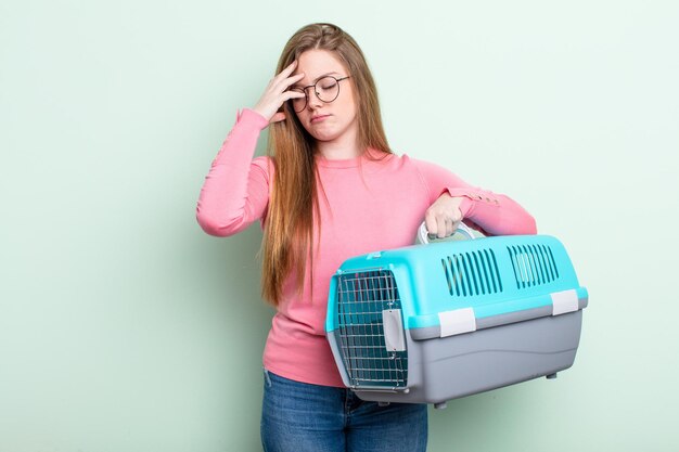 Donna dai capelli rossi che si sente annoiata, frustrata e assonnata dopo un periodo faticoso. concetto di trasportino per animali da viaggio