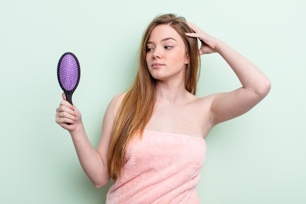 Redhair woman feeling puzzled and confused, scratching head. hair comb concept