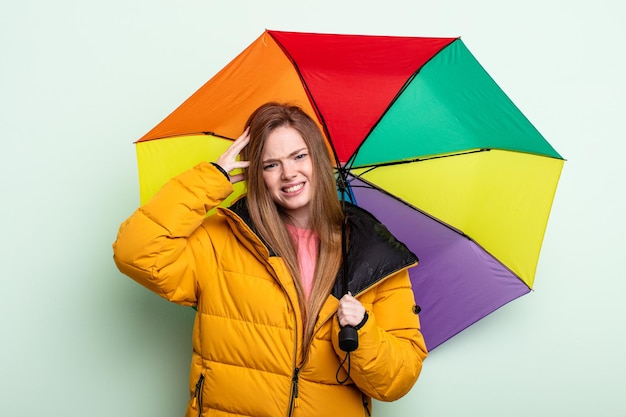 Redhair woman feeling stressed, anxious or scared, with hands on head. umbrella concept