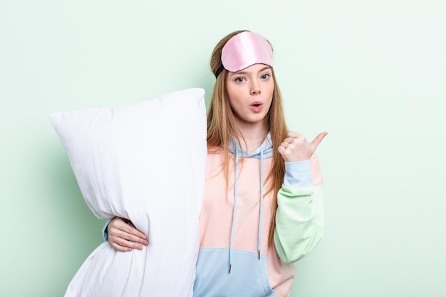 Redhair woman looking astonished in disbelief. pajamas and pillow concept